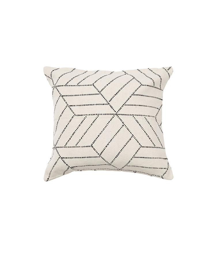 An off-white couch pillow with black linear designs